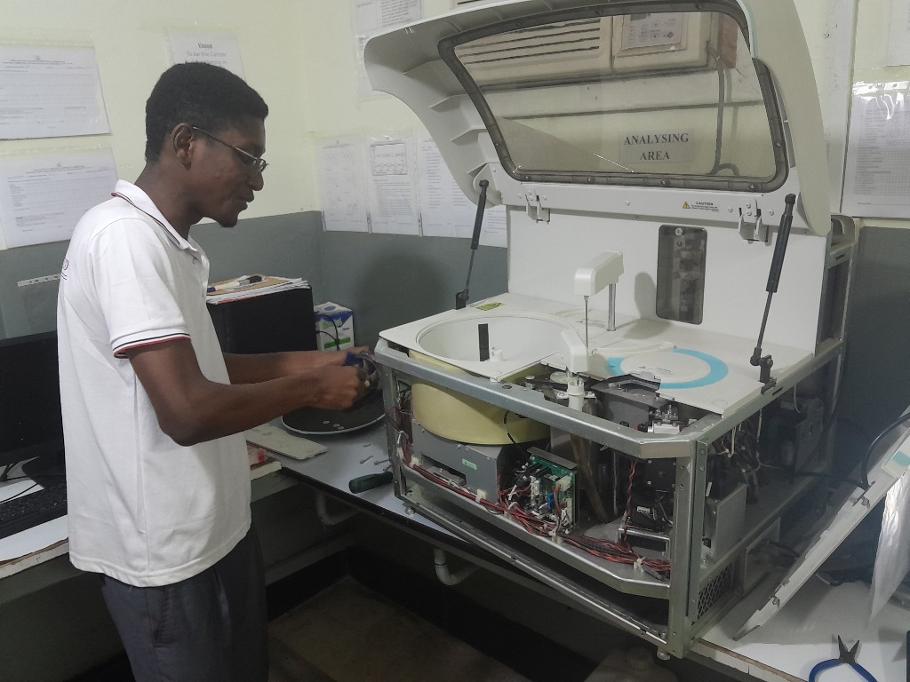 HIL BIOMEDICALS & SYSTEMS LTD Engineer servicing automated laboratory analyzer in Ghana hospital analyzing area